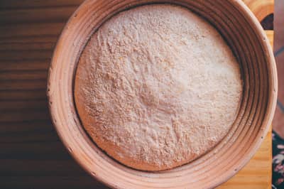 Shaped bread dough proofing in a round floured banneton basket