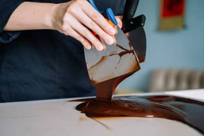 Melted chocolate being poured onto a marble slab for tempering