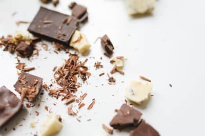 Chunks of pale cocoa butter beside dark chocolate