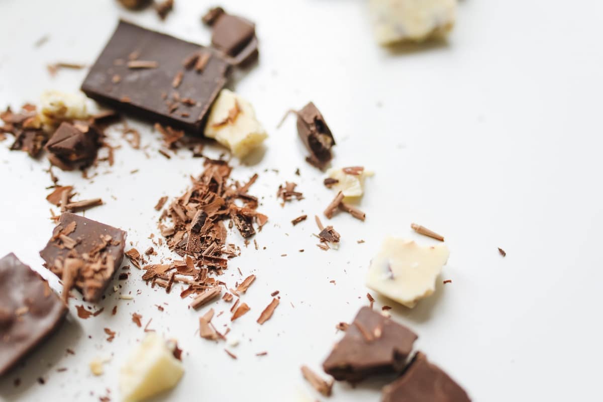 Chunks of pale cocoa butter beside dark chocolate