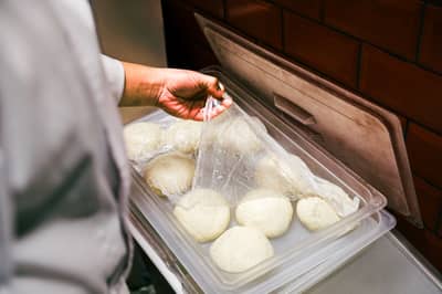 Portioned dough in containers headed for a slow, cold rise in the fridge