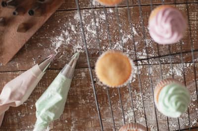 Frosting being piped onto a cupcake with a piping bag