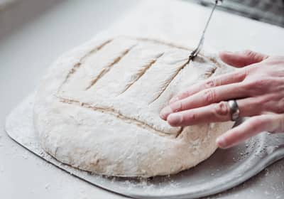 A decorative scoring pattern cut into a flour-dusted loaf