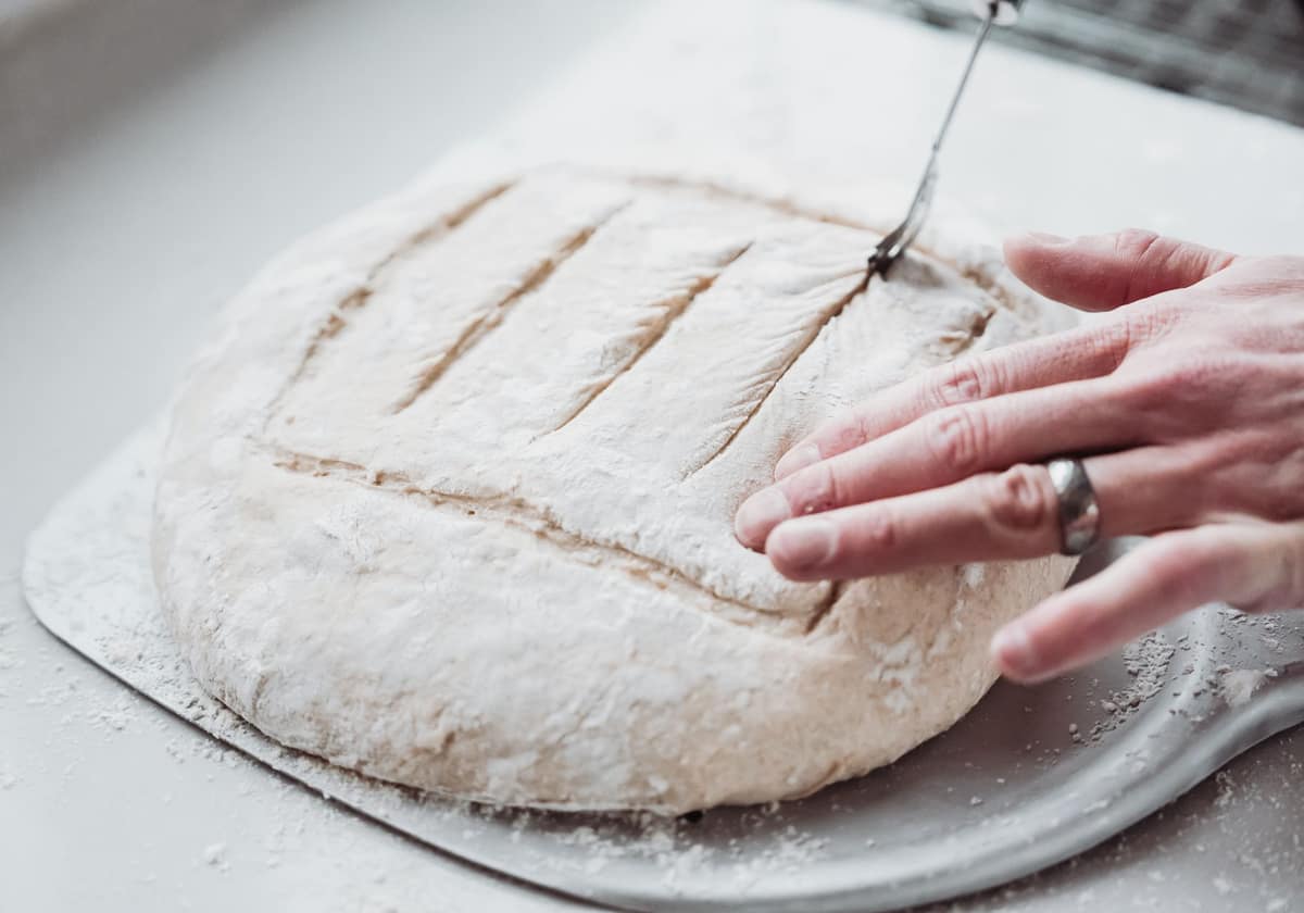 A decorative scoring pattern cut into a flour-dusted loaf