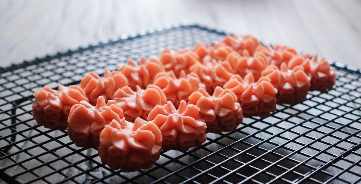 Silky buttercream rosettes piped on a cooling rack