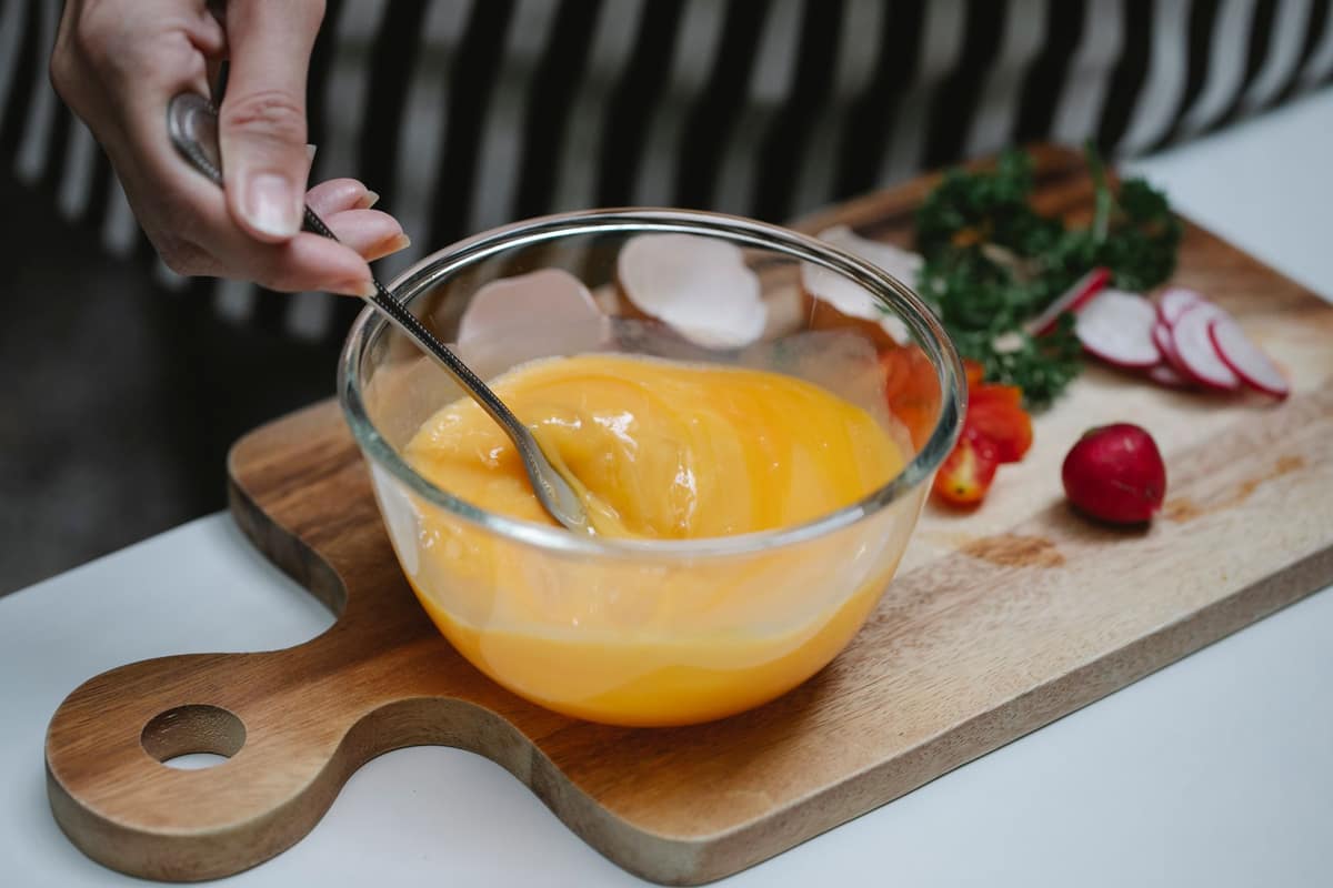 Egg yolks being whisked as warm liquid is added gradually