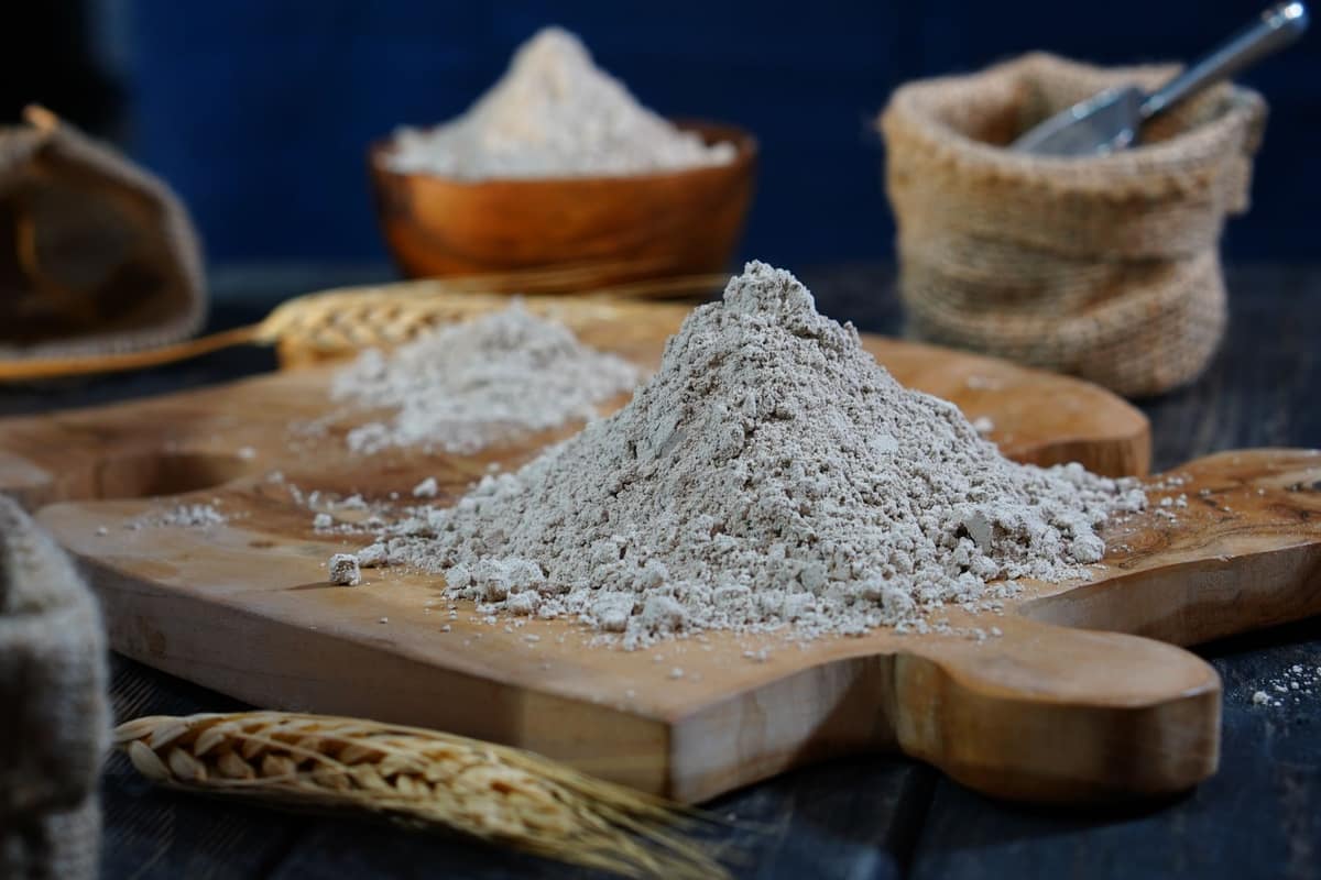 Hands working soft dough in a cloud of wheat flour
